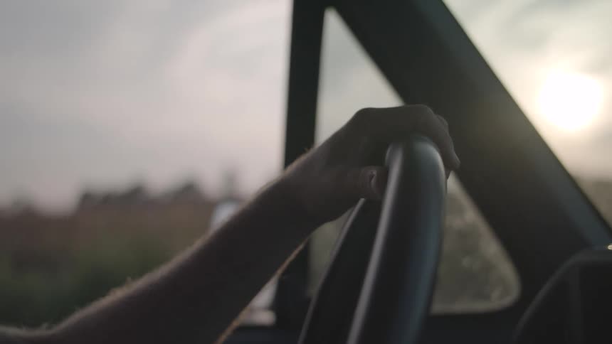 A person inside a car holding the steering wheel and driving