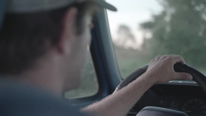 Man in cap driving a car during daytime