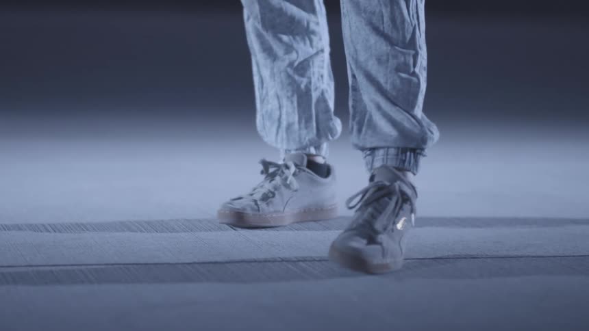 Person jumps and moves their feet while dancing on a pale floor