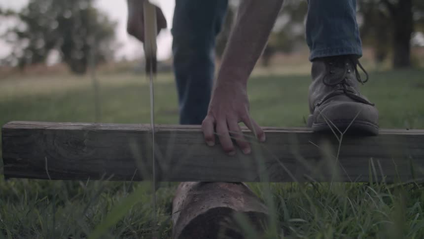 A man saws a piece of wood in half