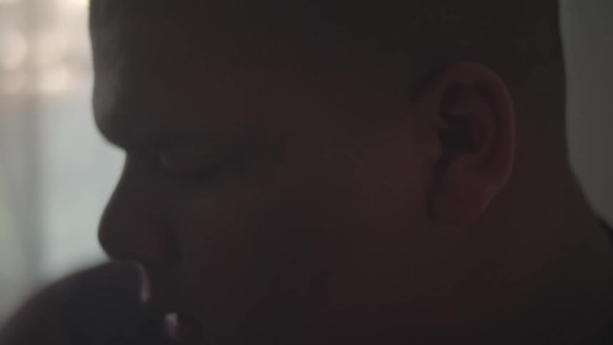 A young teenage boy is inside a room at midday nodding his head up and down