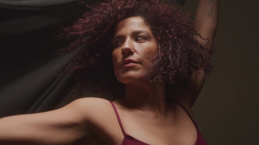 Curly haired model woman twirling a black scarf in a studio setting