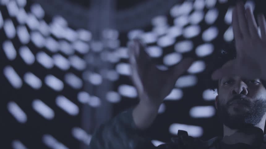 A man dances in front of a lighted background