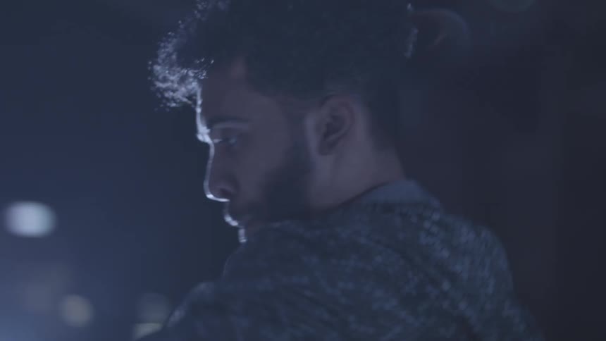 Closeup of a young mans face as he dances illuminated by vibrant city lights at night
