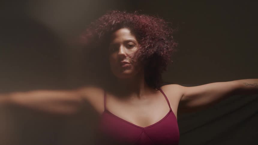 Woman stands with her arms extended while air blows through her hair