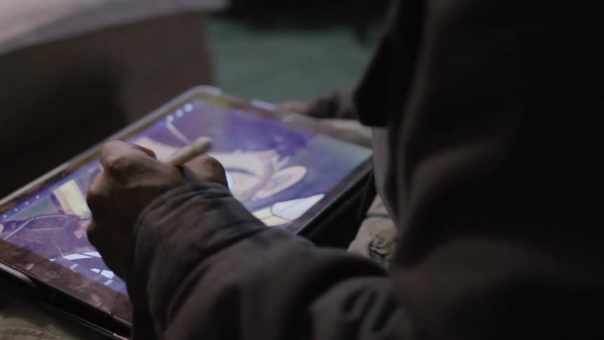 Pair of hands with a pen drawing and painting on a tablet