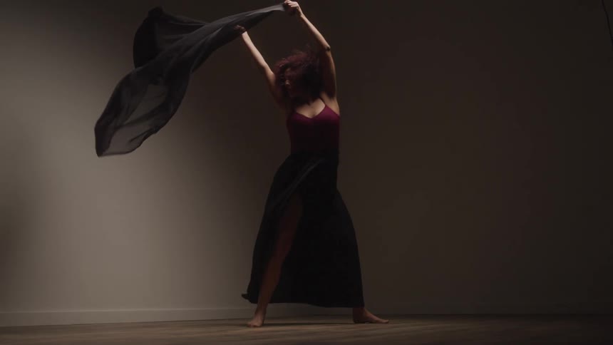 Female dancer dances in a room with a wooden floor