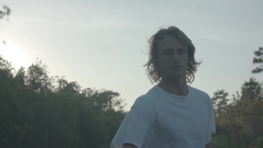 Young man holds a strap while being pulled along a rural highway on a skateboard