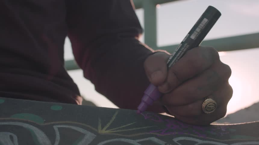 Artist sits near the window on a sunny day and draws with a marker