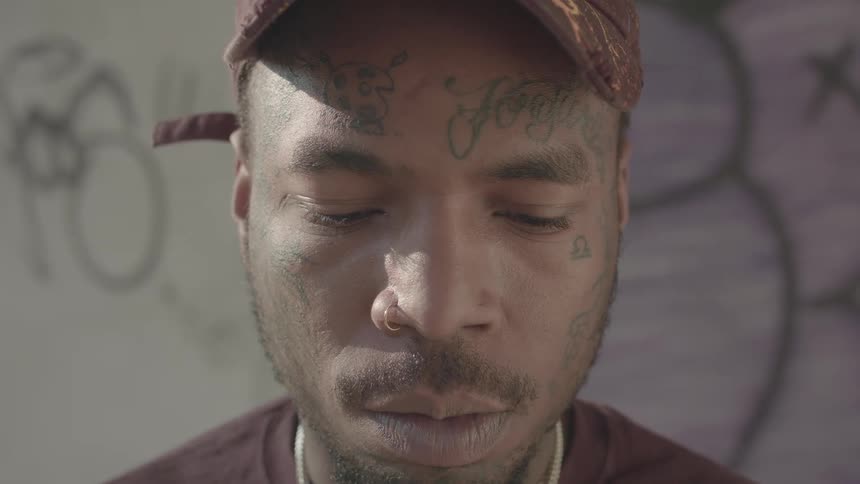 Portrait of a man wearing a cap and with a tattooed face
