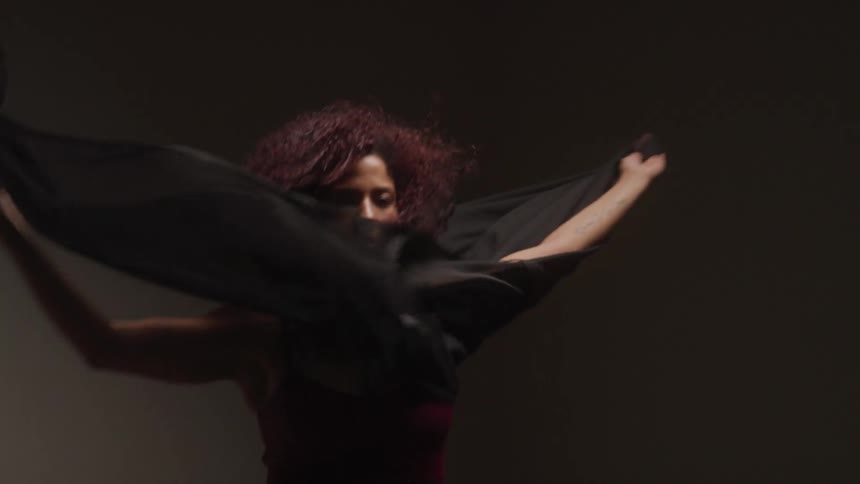 A woman is using a large piece of fabric as a dancing prop
