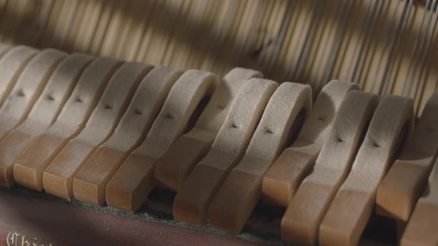 A closeup view reveals the interior of a piano showcasing the hammers hitting the strings