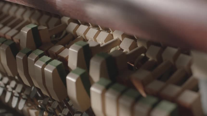 A closeup view shows the intricate mechanism inside a piano with hammers striking the strings