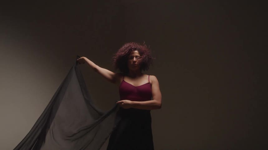 Woman moves through poses while holding a thin black wrap
