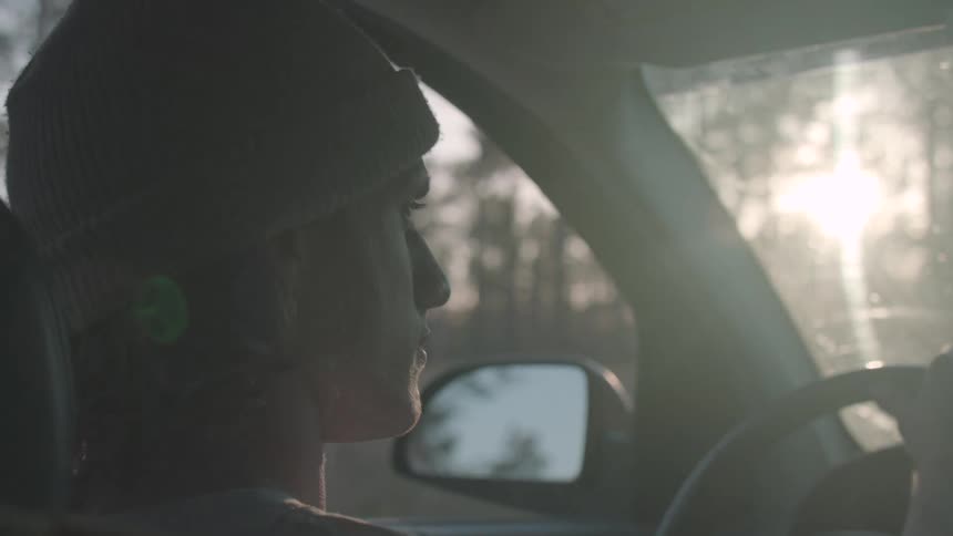 Rewritten a young man wearing a hat is driving alone in a car on a sunny day