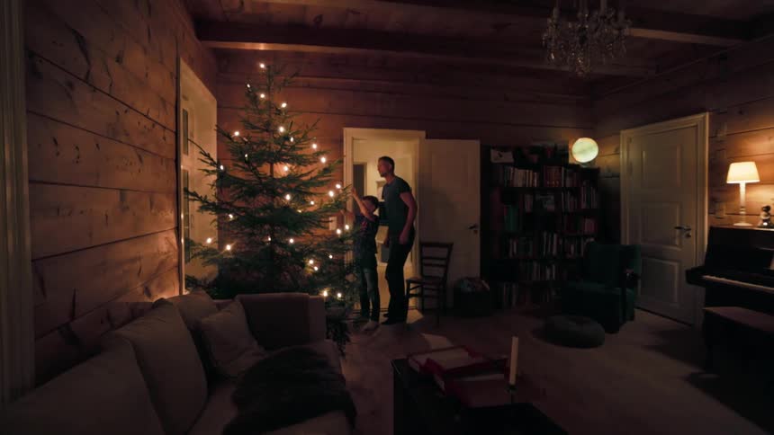 Father and son decorating a christmas tree at night in the living room