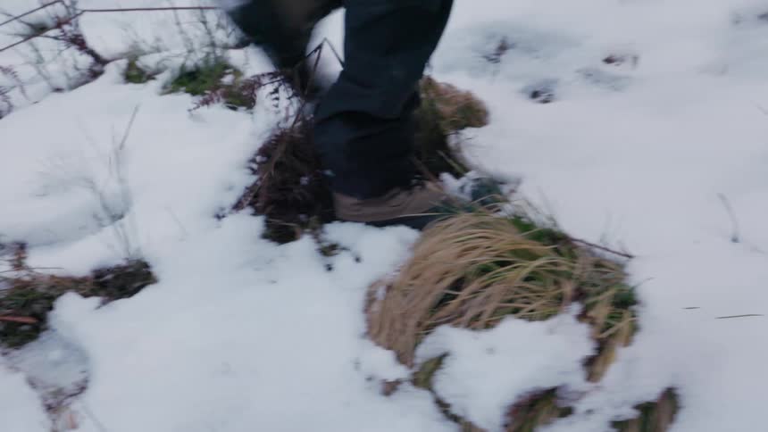 Legs of two people in boots walking in a natural environment with snow