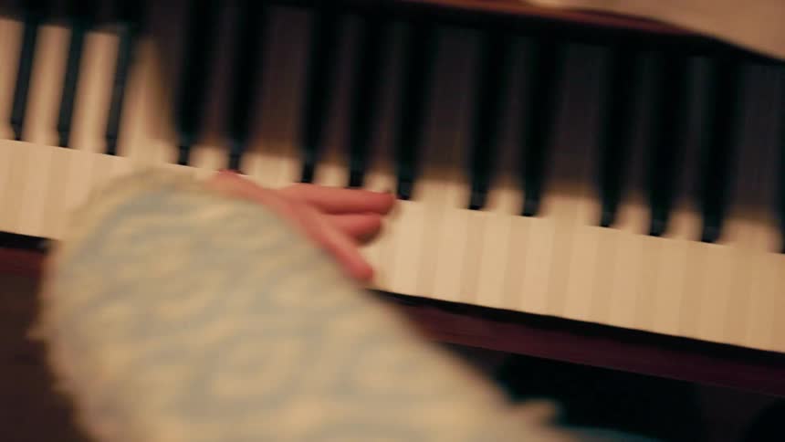 Close up of a hand being passed over the keys of a piano