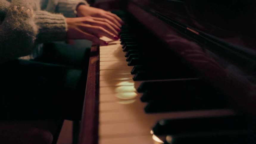 Woman in sweater sitting playing piano