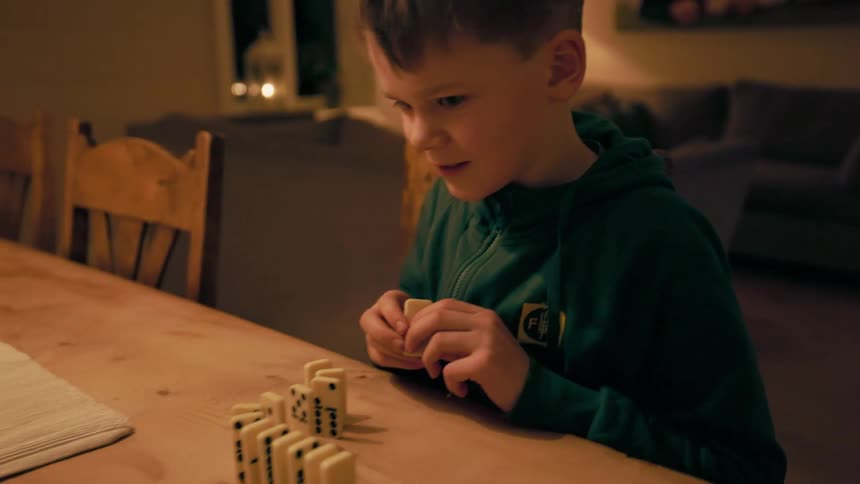 A boy and another person set up dominoes together