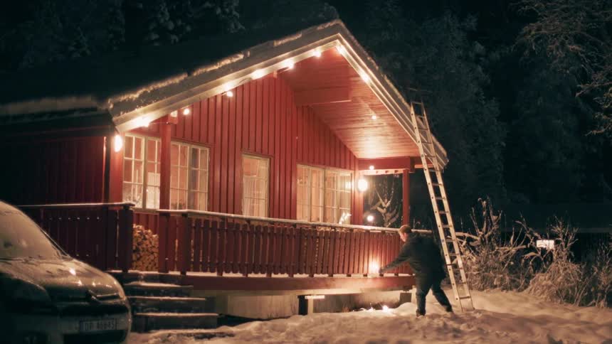 Man adjusting a ladder towards the roof of a house at night