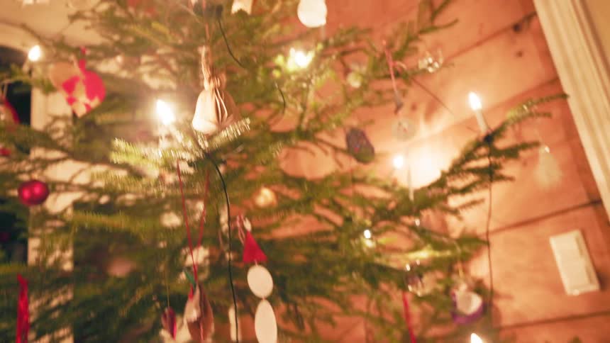 Christmas tree decorated with lights and gifts in the corner of a living room