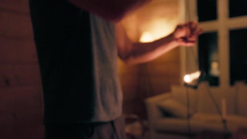 A persons hands are manipulating a string of warmtoned christmas lights in a softly illuminated living room