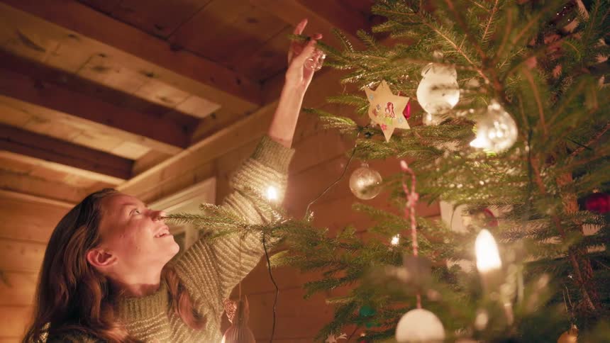 Woman decorating a christmas tree with a light bulb