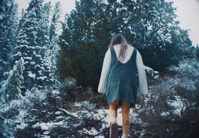 A woman hiking uphill crouches to touch the snow