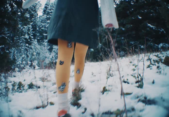 The woman is walking slowly uphill in the snow