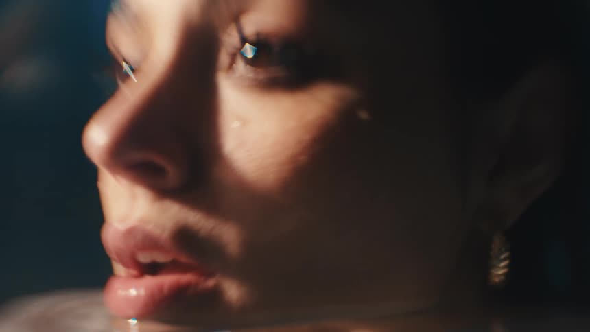 The face of a young woman who has her face wet and she is wearing a gold earring