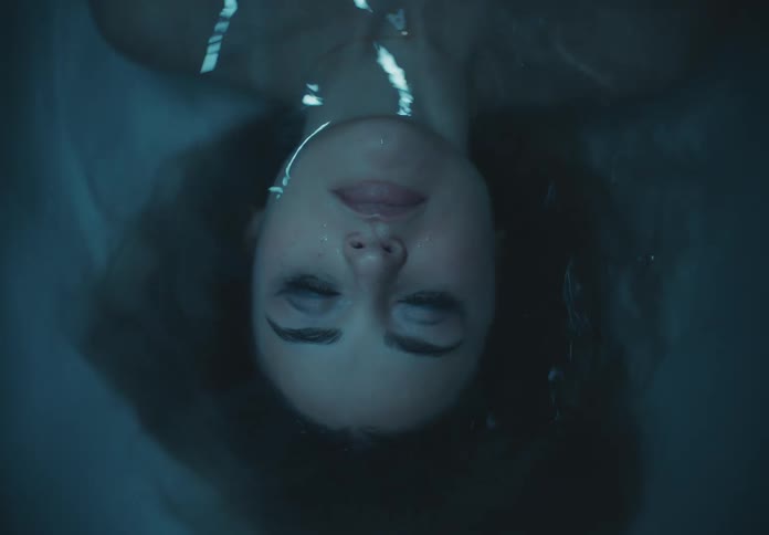 A woman is laying in the tub with her eyes closed