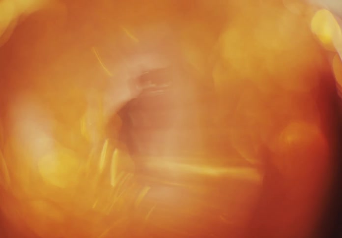 A blurred abstract pattern of warm orange and yellow tones with bright highlights