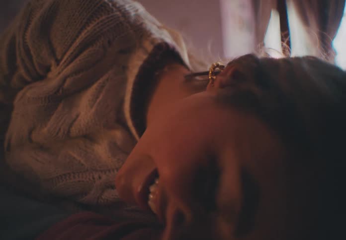 Woman lying on her bed in a bedroom with a curved bay window smiles