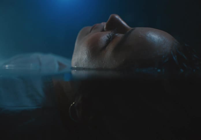 The face of a woman floating on the surface of water while blinking her eye
