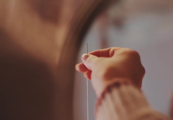 A woman is sewing in front of a mirror