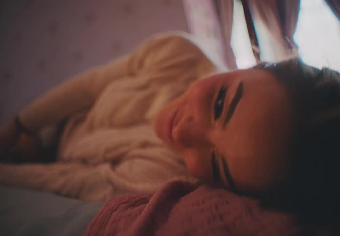 Woman with happy expression lying on bed