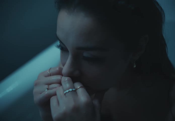 A woman looks sad while sitting in the bathtub