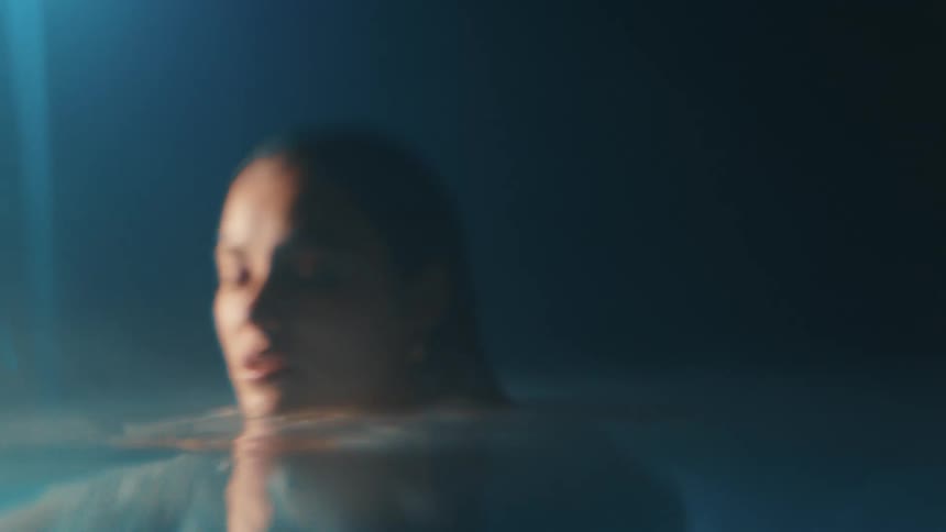 The face of a woman who has her body in the water and she is looking forward