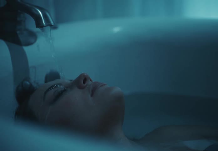 The tub faucet is pouring on the womans face