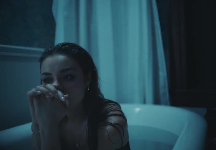 Upset woman sits in a filled bathtub while dressed