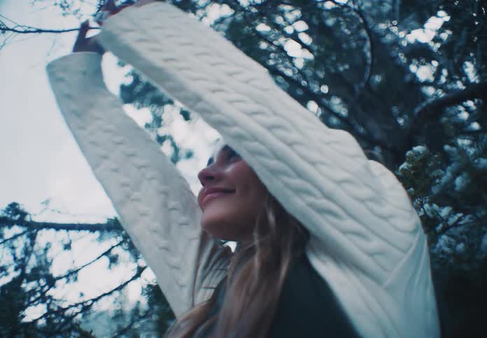 Woman standing near a frosted tree stretches and smiles