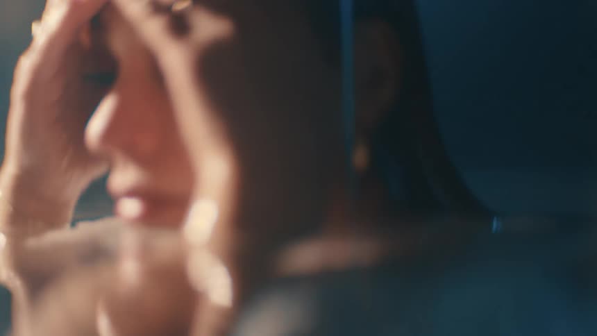 A woman sits quietly in a bath lost in thought as soft light washes over her face