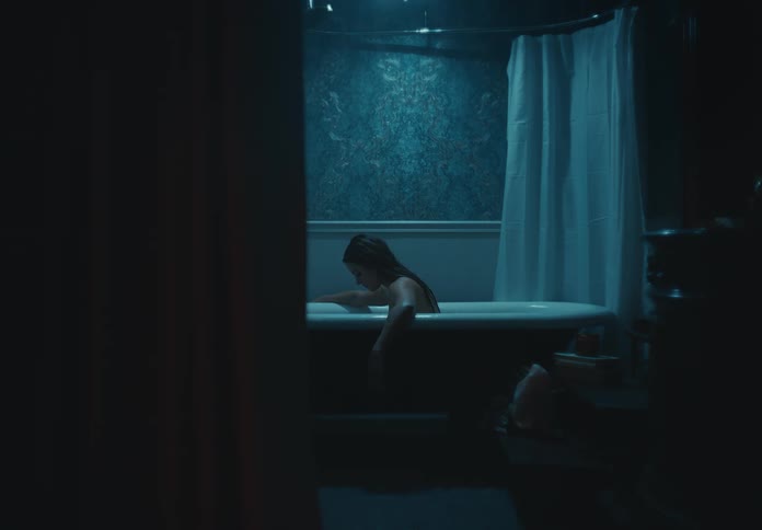 Woman dangles her arms over the edge of a tub before drawing them back in again