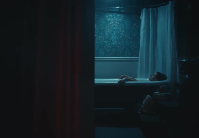 Woman relaxes while taking a bath in a dimly lit bathroom