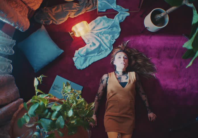 A woman lying on a pink carpeted floor and she is vomiting