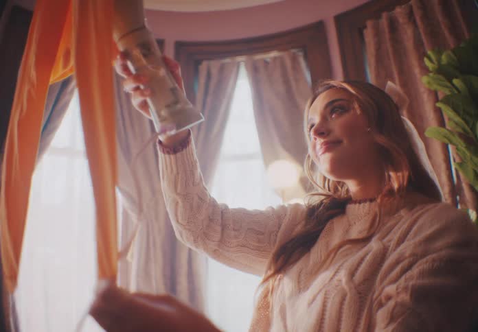 Woman standing near the windows steams her clothes with a handheld steamer during the daytime