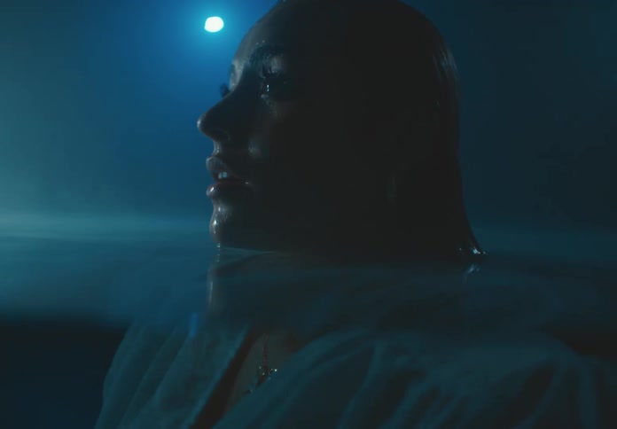 Submerged woman wearing clothes breaks through the surface of the water at night