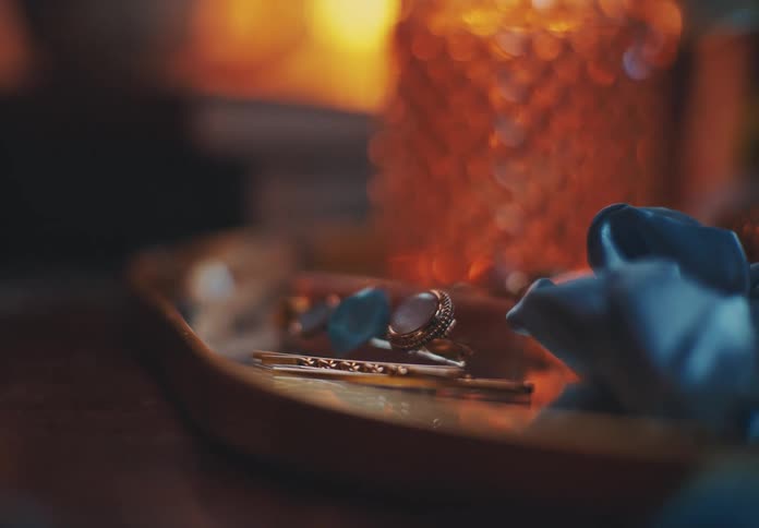 Jewelry and a wristwatch are arranged on a tray with a blue napkin placed beside it