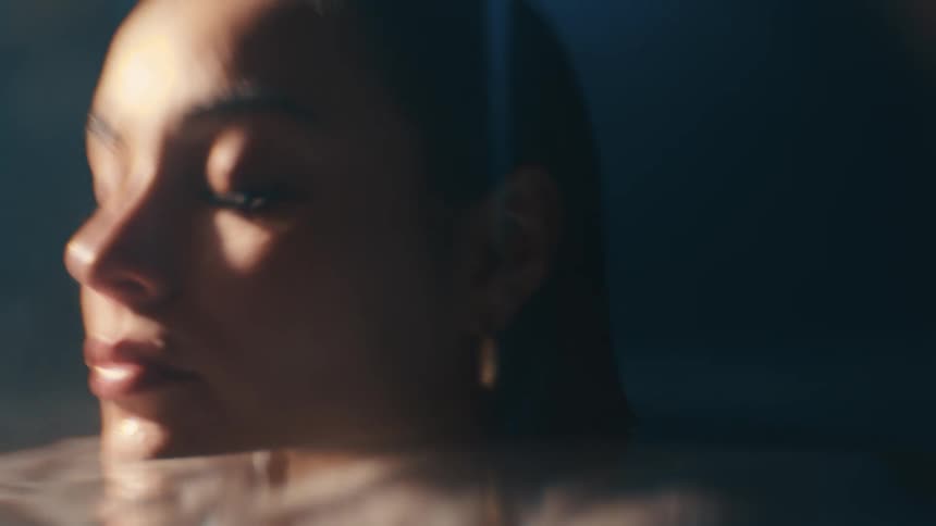 A woman submerged in a bathtub rubbing water off her face